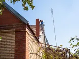 Chimney sweep in winter gear working on a rooftop chimney